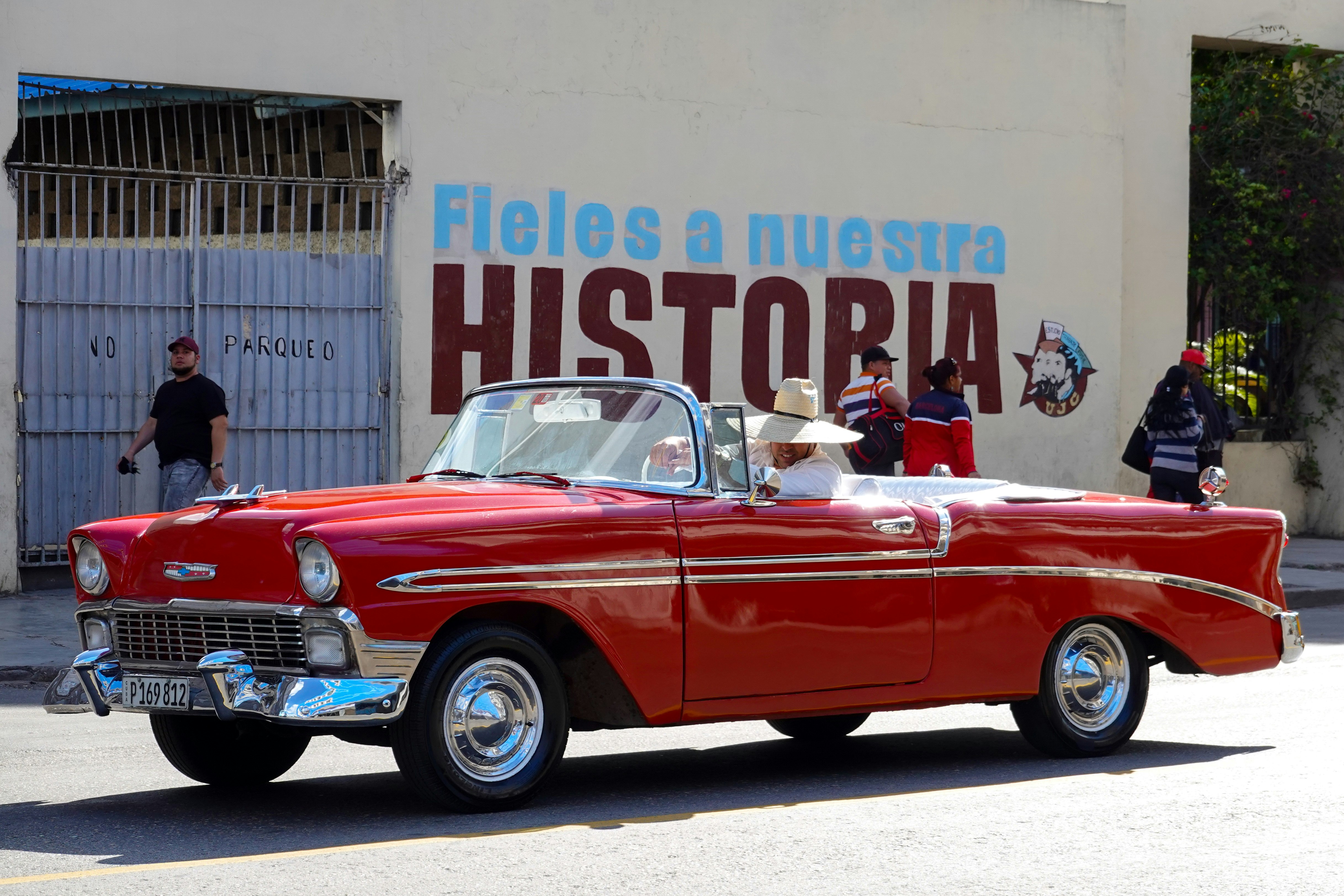 red convertible car in front of people during daytime